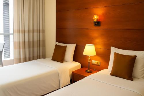 a hotel room with two beds and a lamp at Britannia Suites in Beirut