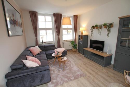a living room with a black couch and a tv at Gästewohnung "Harzliebe" in Halberstadt