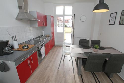 a kitchen with red cabinets and a table with chairs at Gästewohnung "Harzliebe" in Halberstadt