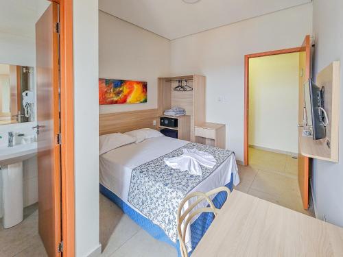 una piccola camera da letto con un letto e una televisione di Hotel Verdes Mares a Ouro Branco