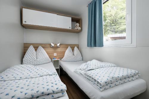 a bedroom with two twin beds and a window at KNAUS Campingpark Nassau in Nassau