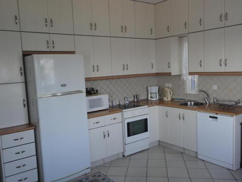 a kitchen with white cabinets and a white refrigerator at Anemomylos Houses in Koufonisia