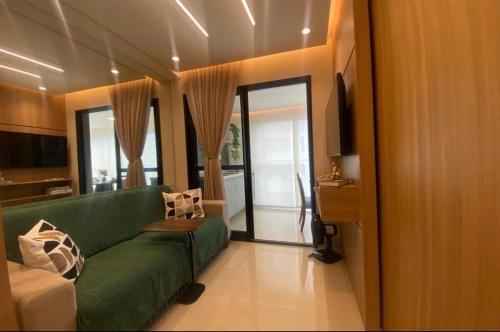 sala de estar con sofá verde y algunas ventanas en Charming apartment with balcony a few minutes apto from Barra, en Salvador