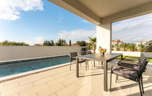 Gorgeous Home In Zaton في زاتون: فناء مع طاولة وكراسي بجوار حمام سباحة
