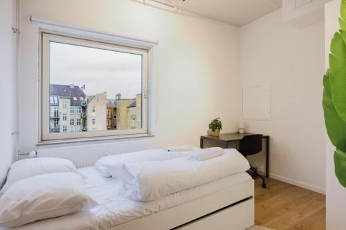 een witte slaapkamer met een groot raam en een bed bij Copenhagen Getaway Cute Studio for Two 7 in Kopenhagen