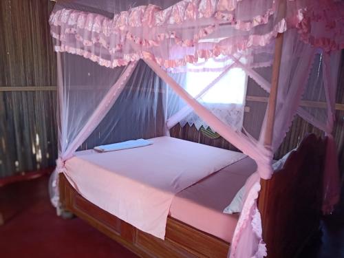 a bedroom with a canopy bed with a window at Maison Des Voyageurs in Ambanja