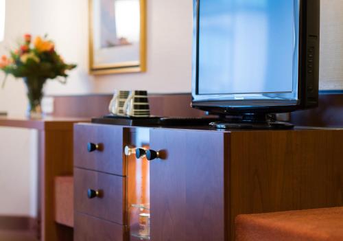a tv sitting on top of a wooden cabinet at Hotel Fulda Mitte in Fulda