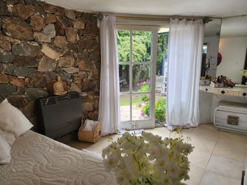 a bedroom with a stone wall and a bed and a window at Casa del Cielo in La Cumbre