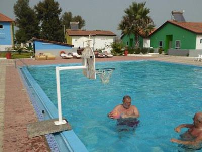 Sand Beach Holiday Resort في سيريكوندا: رجلان يلعبان كرة السلة في حمام سباحة