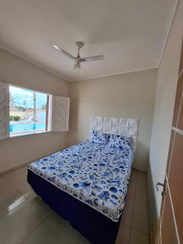 ein Schlafzimmer mit einem Bett mit blauer Bettdecke und einem Fenster in der Unterkunft Chalé das Palmeiras in Itabaiana