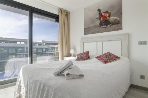 a bedroom with a white bed and a large window at Atico de Lux Zahara in Zahara de los Atunes