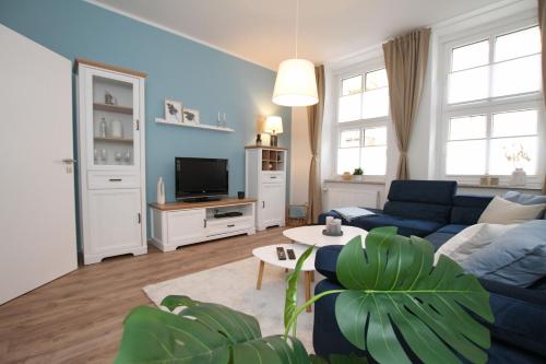 a living room with a blue couch and a tv at Gästewohnung "ZeitRaum" in Halberstadt