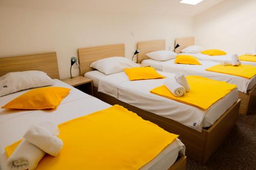 a room with three beds with yellow and white sheets at London Rooms Zagreb Airport in Velika Gorica
