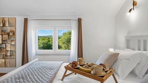 a white bedroom with a bed and a tray of food at Holiday house Hedonica by Villas Guide in Mirlović Zagora