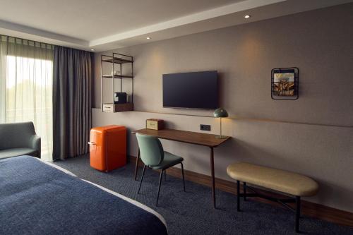 a hotel room with a desk and a television at Van der Valk Hotel Stein Urmond in Urmond
