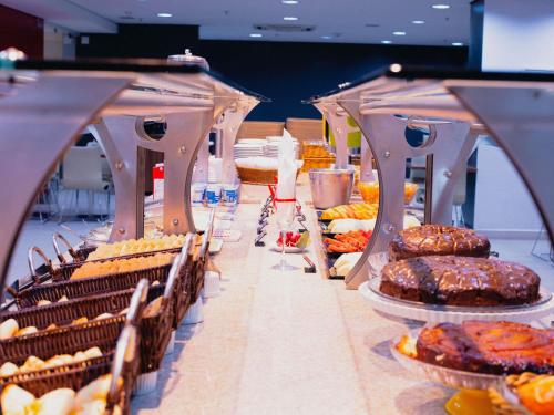 uma linha de buffet com diferentes tipos de bolos e doces em ibis Curitiba Shopping em Curitiba