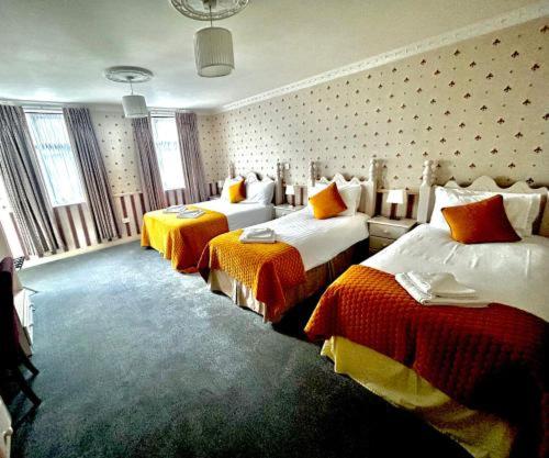 Una habitación de hotel con dos camas con tonos naranja y blanco. en The Royal Hotel, en Arklow