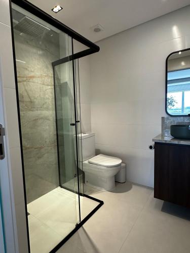 a bathroom with a toilet and a glass shower at Studio New York in Imbituba