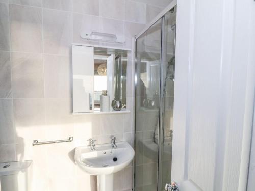 a white bathroom with a sink and a shower at Dunholme in Holyhead