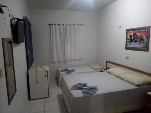 two beds in a small room with a tv at Hotel Internacional in Cianorte