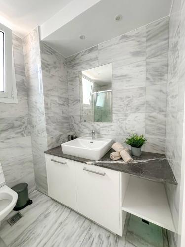 a white bathroom with a sink and a toilet at Seaview Pearl in Mackenzie with Pool & Jacuzzi in Larnaca
