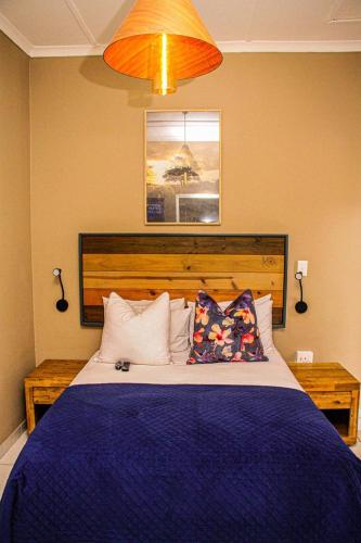 a bedroom with a blue bed with two pillows at Sunshine Lodge in Mthatha