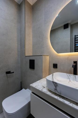 a bathroom with a white sink and a mirror at Luna Minimalist Apartment in Chişinău