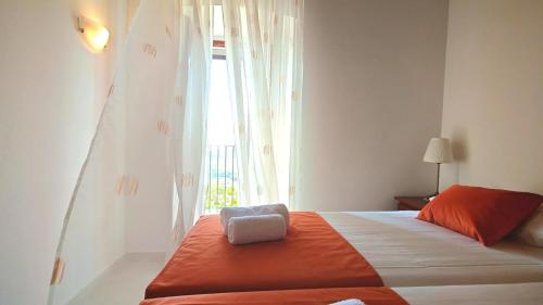 een slaapkamer met een bed met een oranje deken en een raam bij Villa SMOQUIZZA by Villas Guide in Smokvica