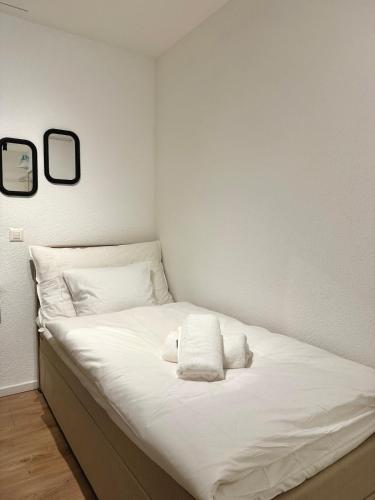 a white bed with two pillows and two mirrors at Studio D'or in Grenchen