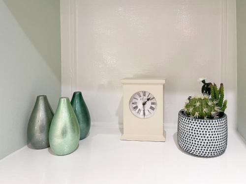 un gruppo di vasi e un orologio su uno scaffale di Riverview Cottage a Hartington