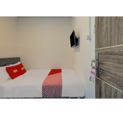 スラバヤにあるCapital O 3198 Sukomanunggal Innの赤い枕付きのベッドが備わる部屋