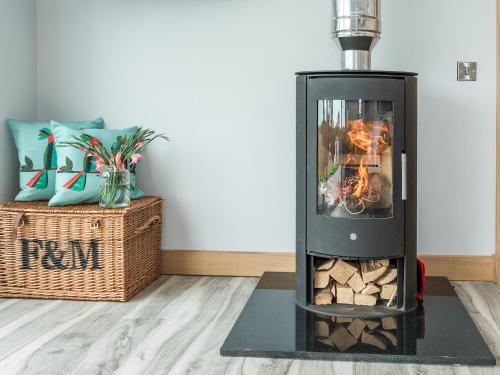 a wood stove with a fire in a living room at High Tide - Uk44283 in Gatehouse of Fleet