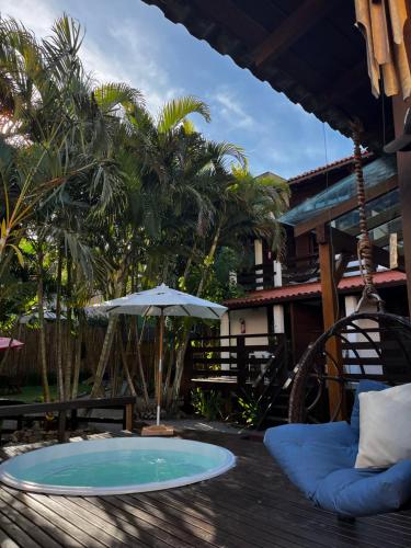 een patio met een tafel en een parasol bij Morada da Xica in Guarda do Embaú