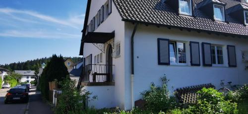 a white house with black shutters on a street at Ferienwohnung Palmenwald in Freudenstadt