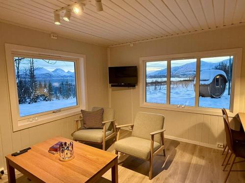 ein Wohnzimmer mit Tisch und Stühlen und Fenstern in der Unterkunft Hiet- Arctic cabin in the norwegian forrest! in Tromsø