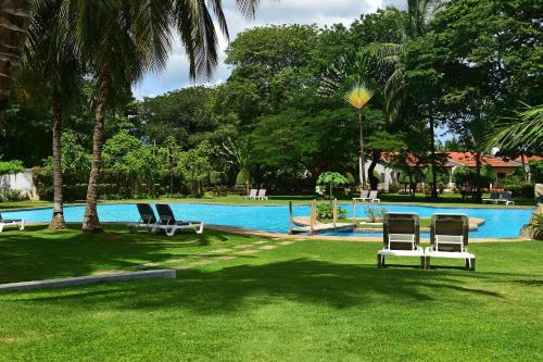 a group of chairs sitting in the grass near a swimming pool at Pestana Miramar São Tomé in São Tomé