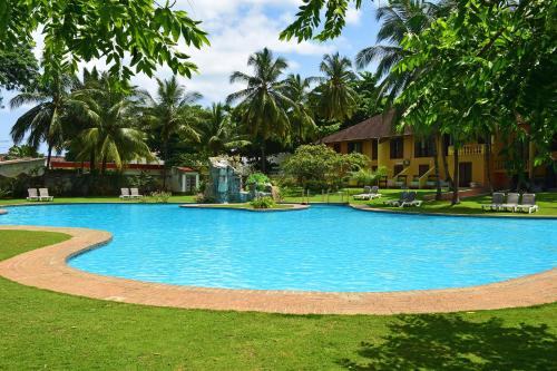 a large blue swimming pool in a yard with palm trees at Pestana Miramar São Tomé in São Tomé