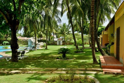 a yard with palm trees and a swimming pool at Pestana Miramar São Tomé in São Tomé