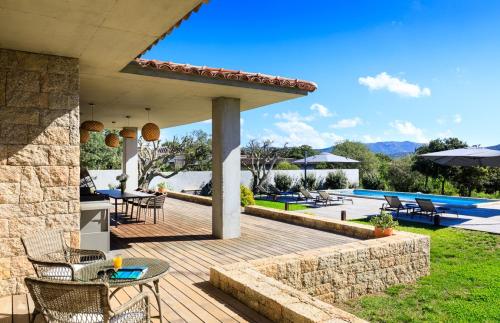 een houten terras met tafels en stoelen en een zwembad bij A Liccia in Pianottoli-Caldarello