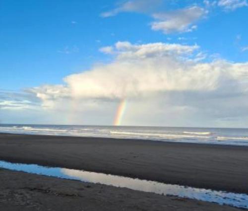 a rainbow in the sky over the ocean with a beach at Alquiler en las Toninas a 2 cuadras del mar in Las Toninas