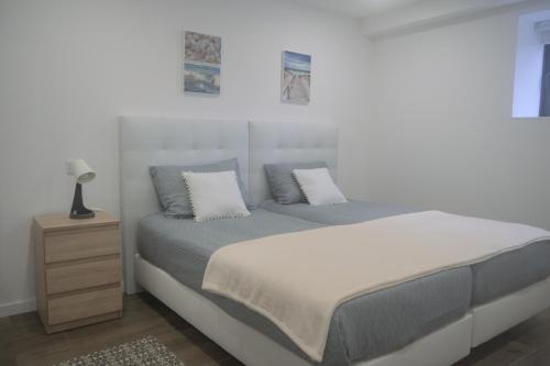 a white bedroom with a bed and a night stand at Casas da Travessoa in Marco de Canaveses