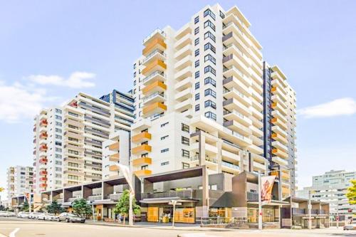 a large white building with balconies on a city street at Burwood Grand Service Apartment in Sydney