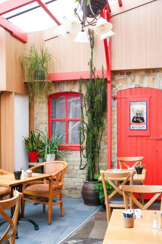 eine Terrasse mit Tischen und Stühlen und einer roten Tür in der Unterkunft Hôtel - Restaurant Au Tonnelier in Bergues