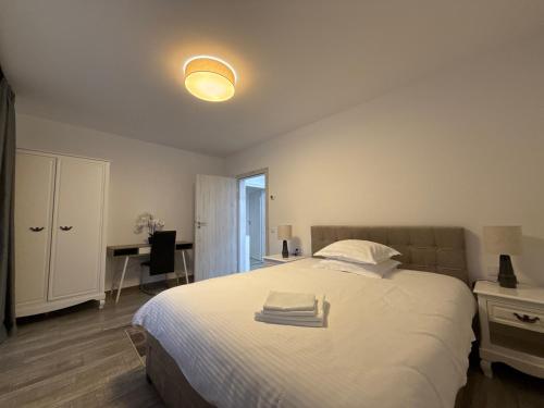 a bedroom with a large white bed with a desk at The View Apartment 3 Bușteni in Buşteni