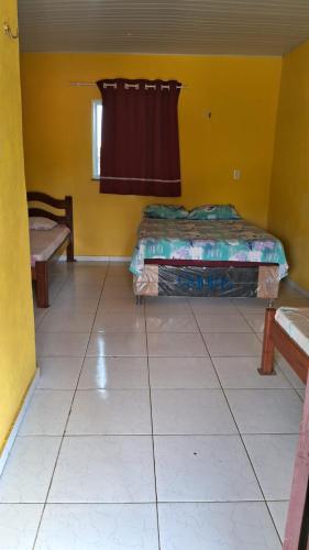 a yellow room with two beds and a window at Pousada dunas in Barroquinha