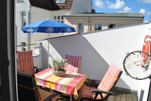 a table and chairs with an umbrella on a balcony at Ferienwohnung Warnemünde Altstadt (RC) in Warnemünde