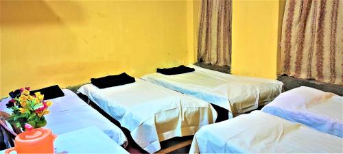 a room with three beds and a yellow wall at The OLD house in Bolpur