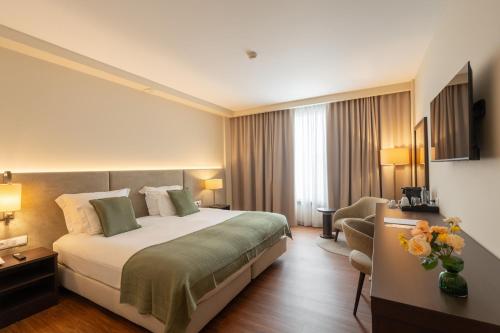 a hotel room with a large bed and a chair at Hotel Premium Porto Maia in Maia