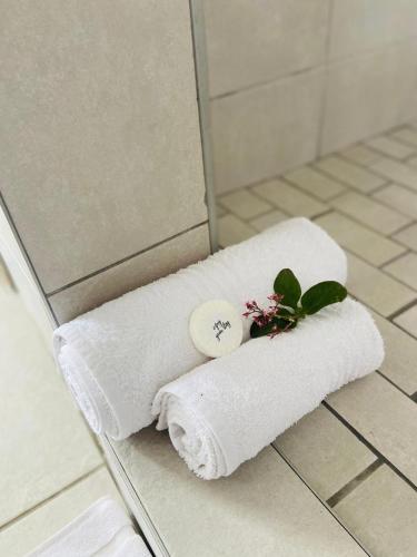a white towel with a button and a plant on it at Sunshine Lodge in Mthatha
