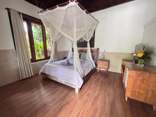 a bedroom with a canopy bed and wooden floors at Balian River Hut in Balian